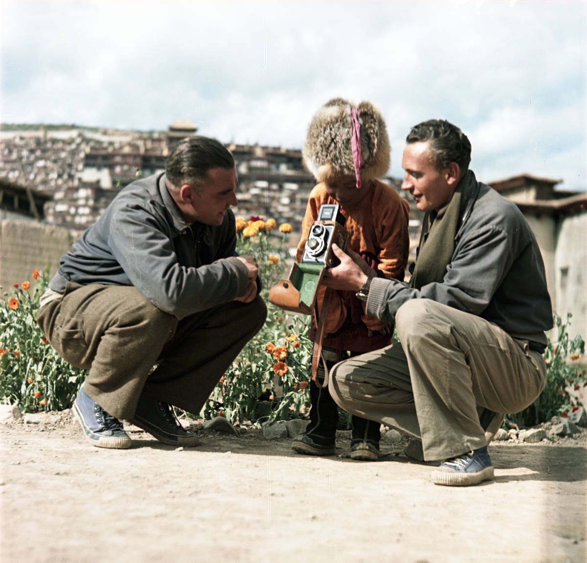 Vladimír Sís, nalevo, uprostřed je tibetský chlapec, který se živě zajímá o zrcadlovku, kterou v ruce drží Josef Vaniš. Fotografováno pod klášterem v Kandze 28. září 1954, publikováno se souhlasem držitele autorských práv Jana Vaniše.
